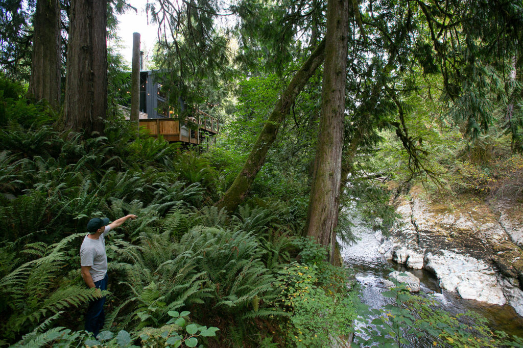 Co-owner Andy Whitcomb stands below Cabin 3 and above a trickling Canyon Creek at Canyon Creek Cabins on Sep. 23, in Granite Falls. (Ryan Berry / The Herald) 

