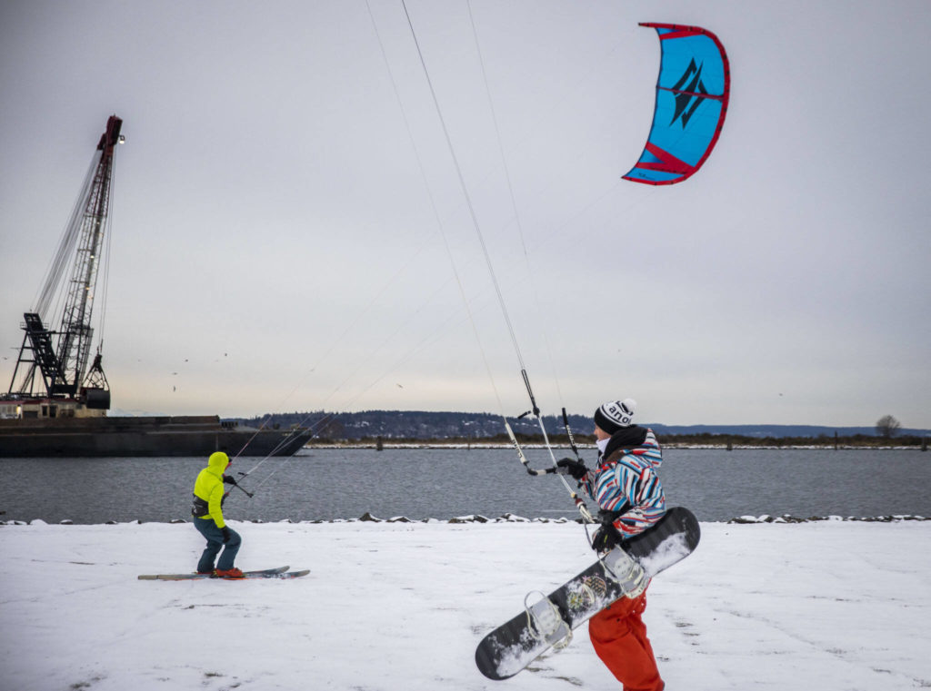 Chris Newton and Trevor Liska snow kite at Boxcar Park on Thursday, in Everett. (Olivia Vanni / The Herald) 
