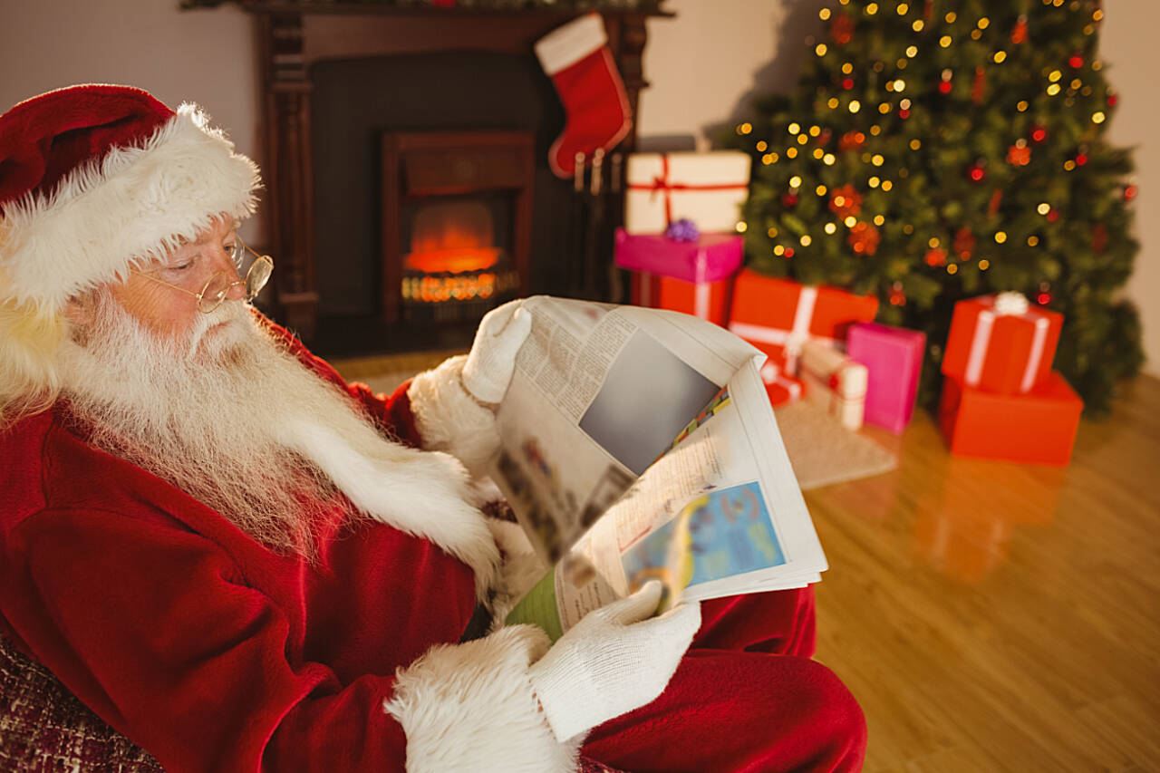 Father christmas reading newspaper on the couch at home in the living room