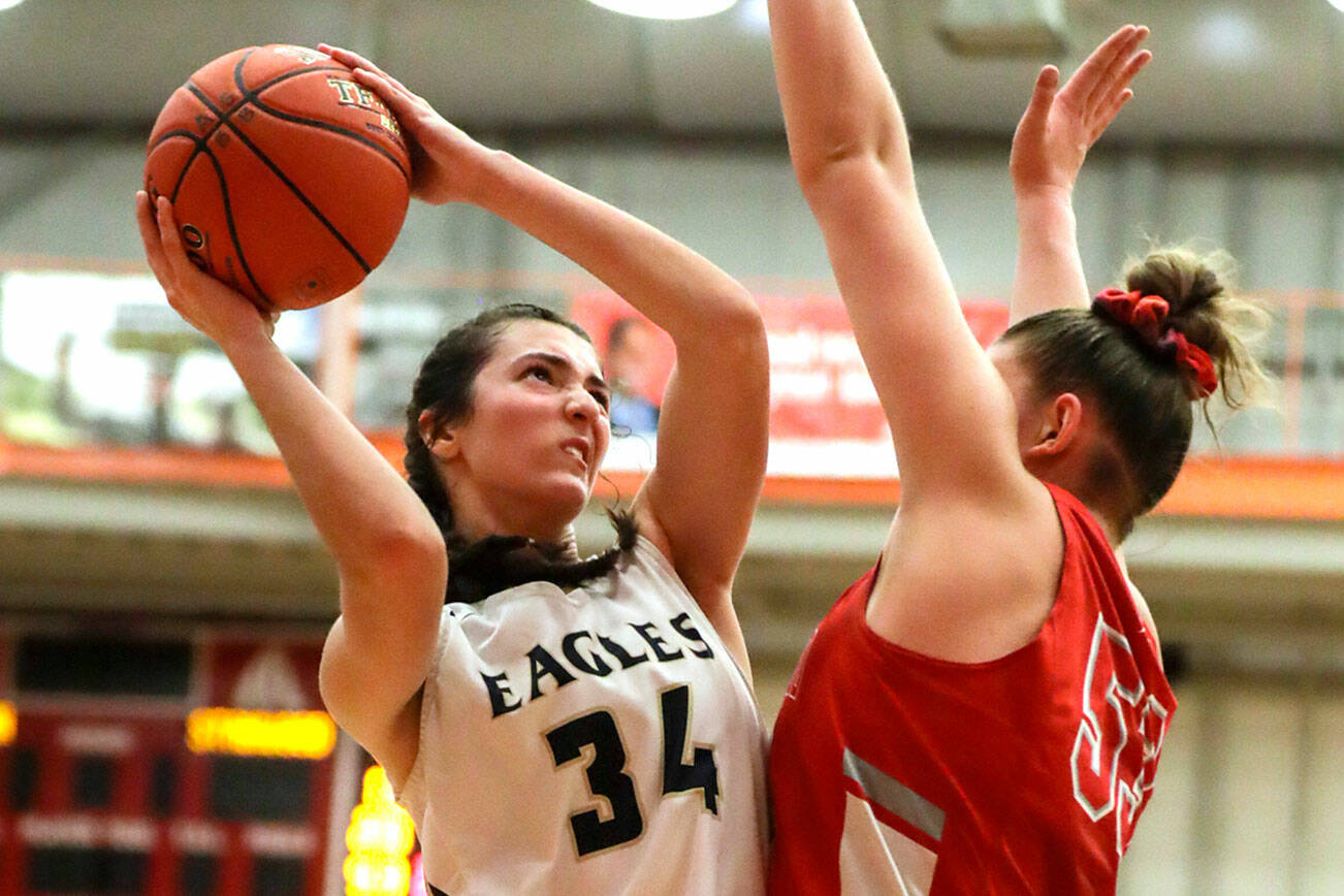 Arlington's Jenna Villa looks to score with Stanwood’s Vivienne Berrett defending Saturday evening at during the 3A District 1 Title game at Everett Community College in Everett, Washington on February 19, 2022. (Kevin Clark / The Herald )