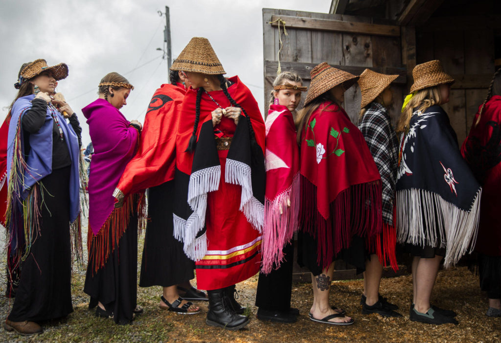 Dancers wait in a single file line to enter the longhouse for Salmon Ceremony on Saturday, June 11, 2022, in Tulalip, Washington. Over 100 people gathered to welcome the King Salmon after two years without the ceremony due to the pandemic. (Olivia Vanni / The Herald)
