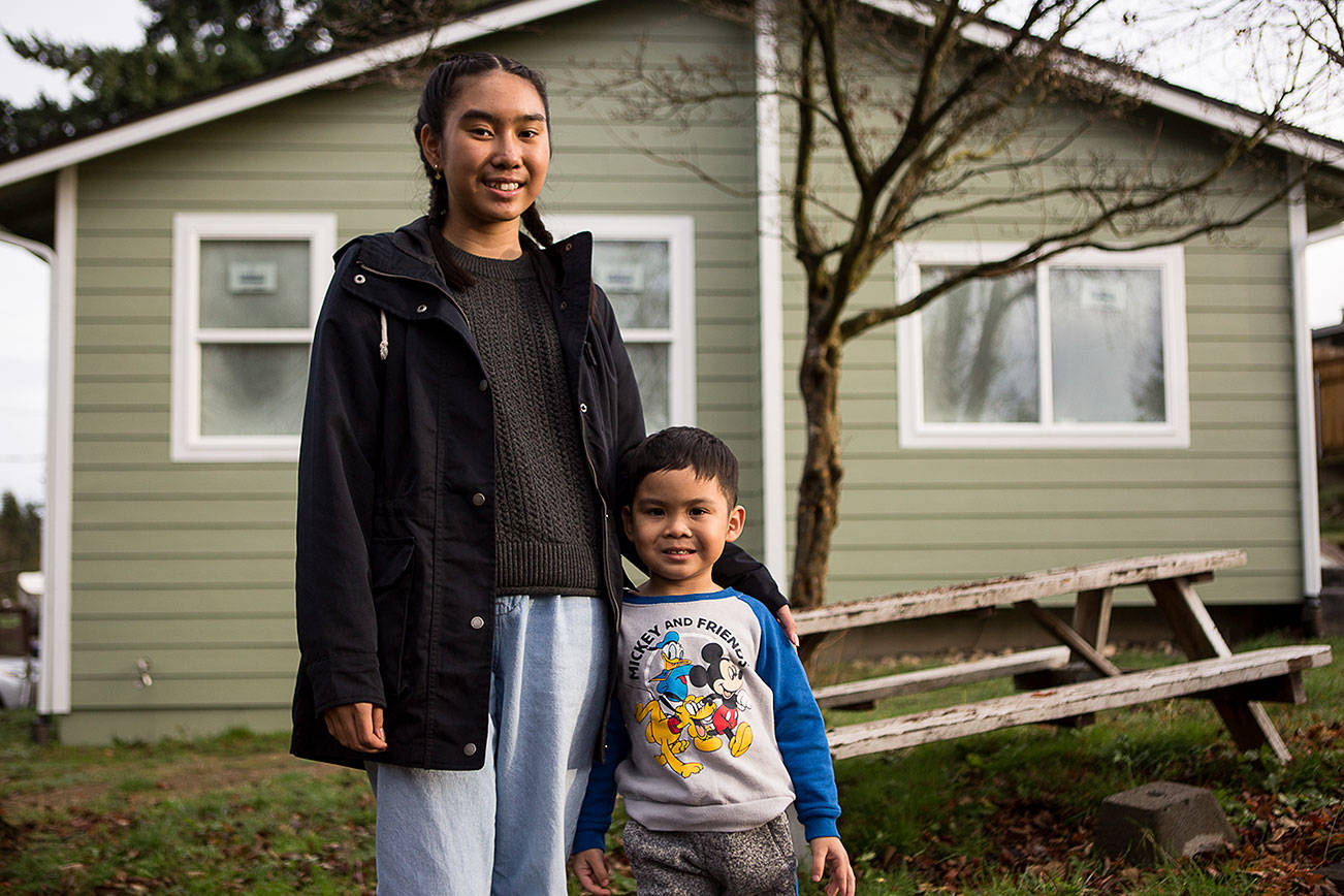 Myli Maytrichith, 12, with little brother Tyson, 4, outside of their home that is currently being rebuilt after catching fire last March on Thursday, Dec. 10, 2020 in Everett, Wa. (Olivia Vanni / The Herald)