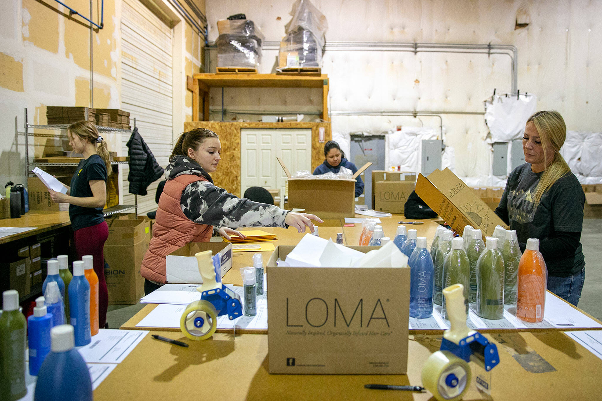 Innovative Salon Products online fulfillment employees, from left, Stephanie Wallem, Bethany Fulcher, Isela Ramirez and Gretchen House, work to get orders put together on Friday, at the company’s facility in Monroe. The company began including pay, benefits and perks to its job listings over a year ago, well ahead of the new statewide mandate to include a pay range on job postings at companies with over 15 employees. (Ryan Berry / The Herald)