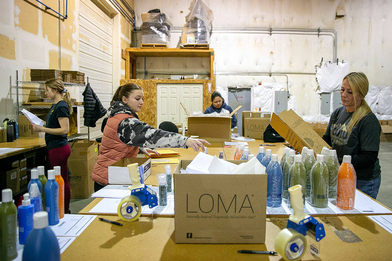 Innovative Salon Products online fulfillment employees, from left, Stephanie Wallem, Bethany Fulcher, Isela Ramirez and Gretchen House, work to get orders put together on Friday, Jan. 6, 2023, at the company’s facility in Monroe, Washington. The company began including pay, benefits and perks to its job listings over a year ago, well ahead of the new statewide mandate to include a pay range on job postings at companies with over 15 employees. (Ryan Berry / The Herald)
