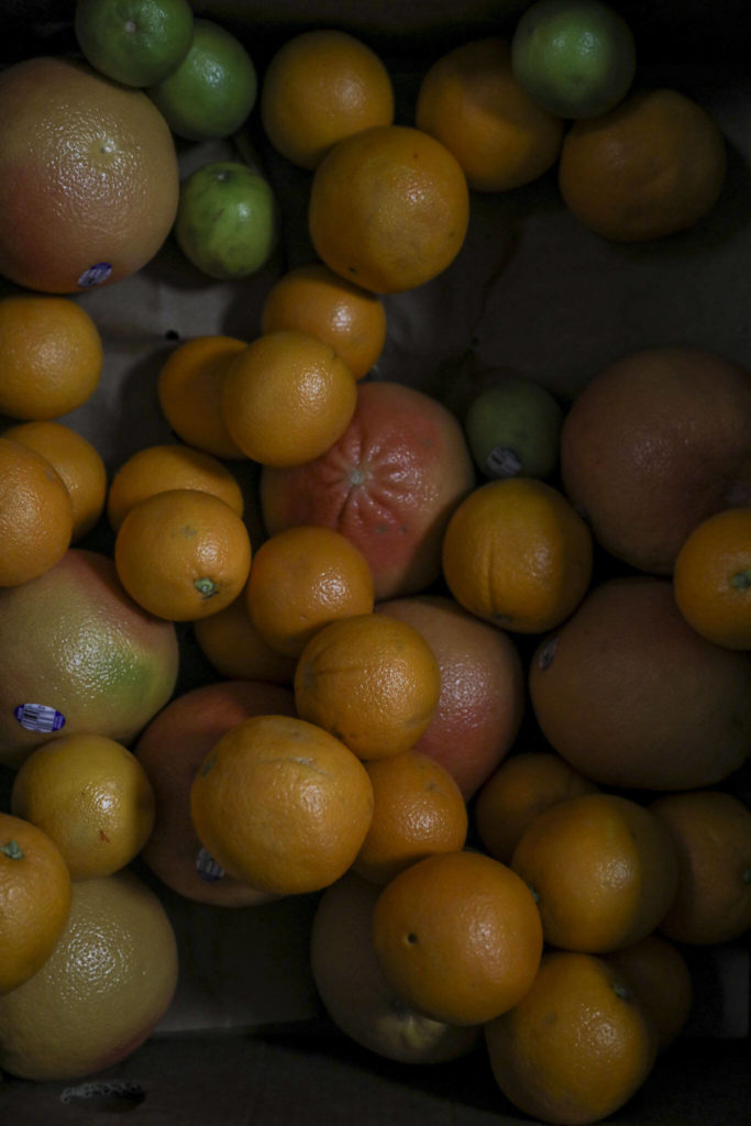 Citrus fruit at the Edmonds Food Bank in Edmonds, on Jan. 16. Scriber Lake High School student Juniper works at the food gank as part of an on-the-job training class that teaches students about career options and goal planning, while also paying them for a part-time internship. (Annie Barker / The Herald)

