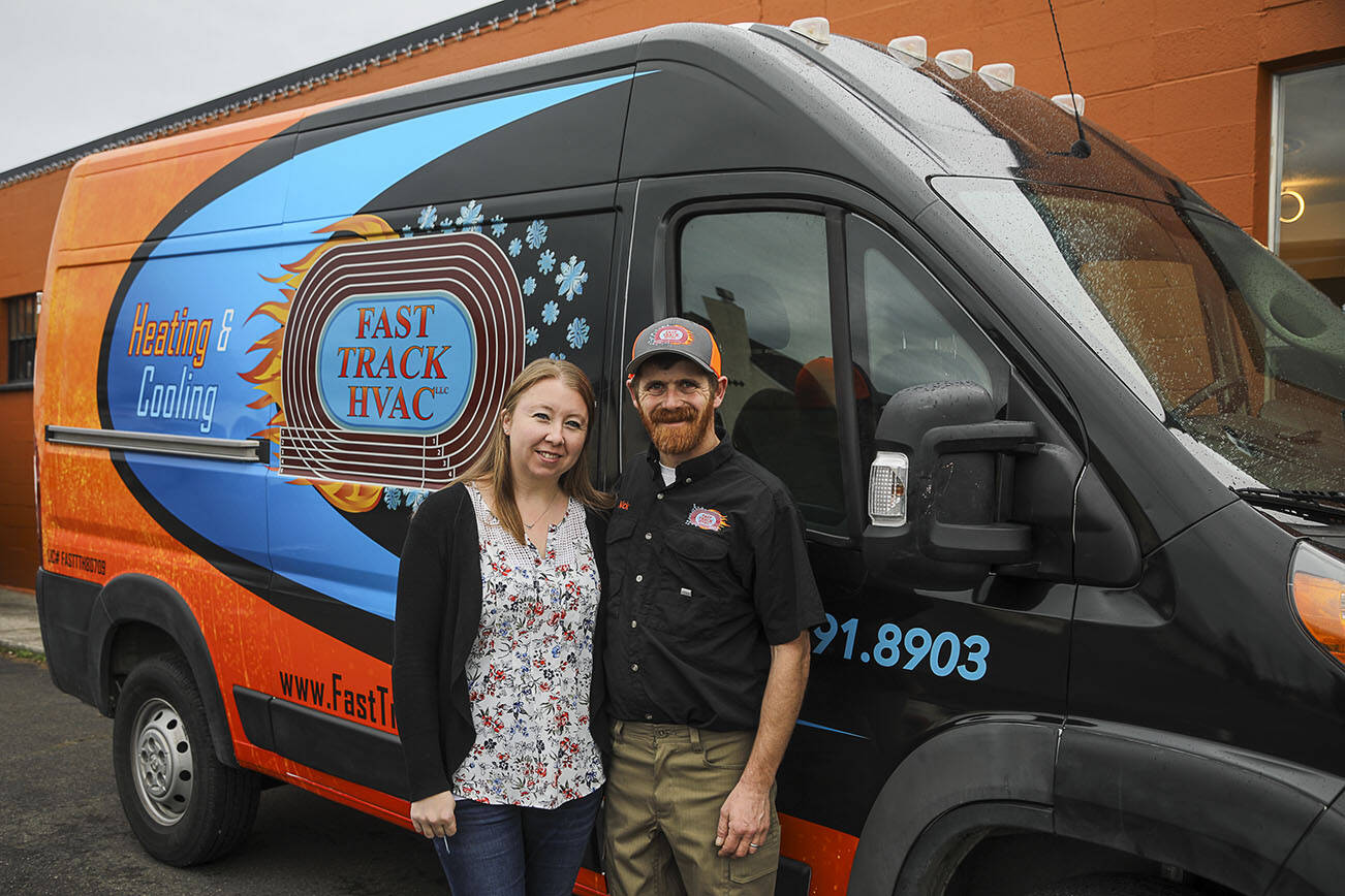 Patricia Cairus, 36, left, and Nick Cairus, 38, right, pose for a photo by one of their vans at Fast Track Hvac in Stanwood on Monday, Jan. 9, 2023. Nick Cairus and Patricia Cairus lost their housing in the recession and were homeless for a number of years. They started a successful HVAC company during the pandemic in a former newspaper printing building.  (Annie Barker / The Herald)