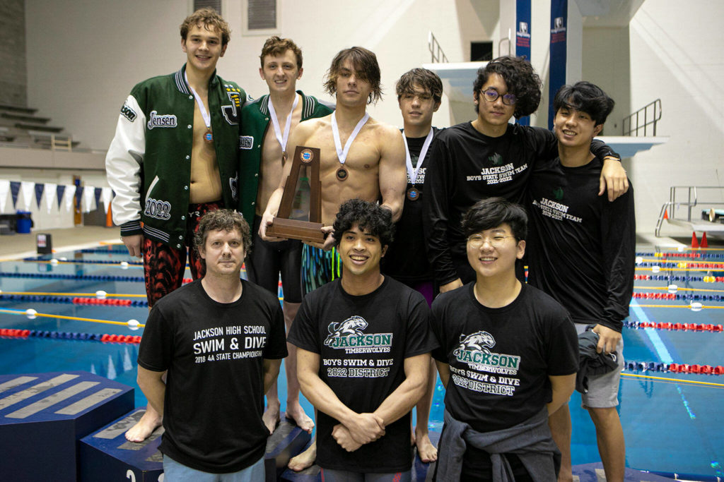 The Jackson boys swimming team celebrates winning a third-place trophy at the Class 4A boys swim and dive championships on Feb. 19, 2022, at King County Aquatic Center in Federal Way. (Ryan Berry / The Herald)
