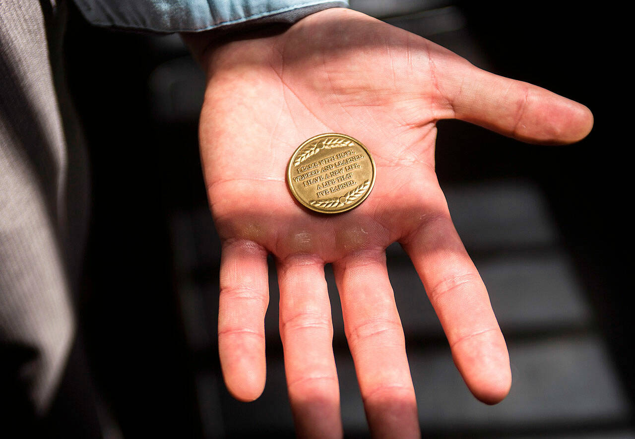 A man displays a commemorative Drug Court graduation coin that reads, “I came with hope, worked and learned. I have a new life. A life that I’ve earned.” Marysville recently passed an ordinance it hopes can be used to persuade more to seek treatment to drug addictions. (Olivia Vanni / The Herald file photo)