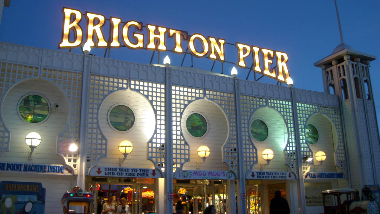 The Brighton Pier glitters at the shore of the English Channel.