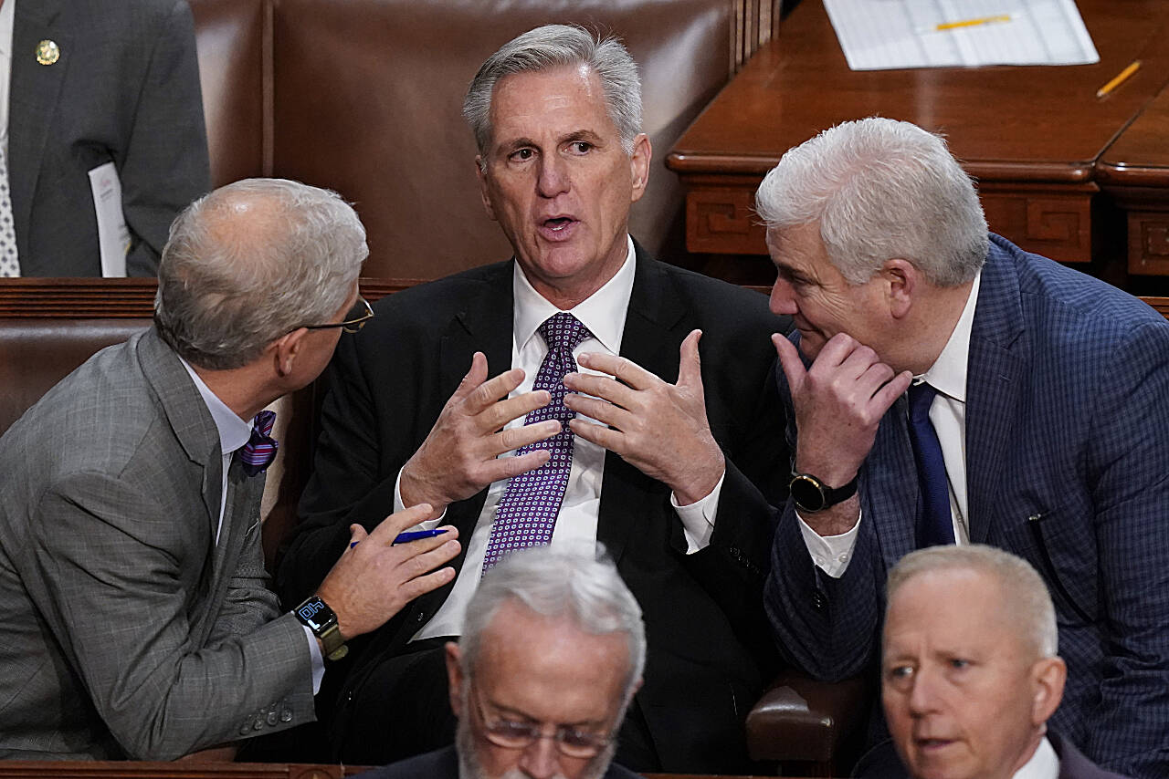 Rep. Patrick McHenry, R-N.C., (left) and Rep. Tom Emmer, R-Minn., (right) speak with Rep. Kevin McCarthy, R-Calif., in the House chamber as the House meets for a second day to elect a speaker and convene the 118th Congress in Washington, D.C., Wednesday. (Alex Brandon / Associated Press)