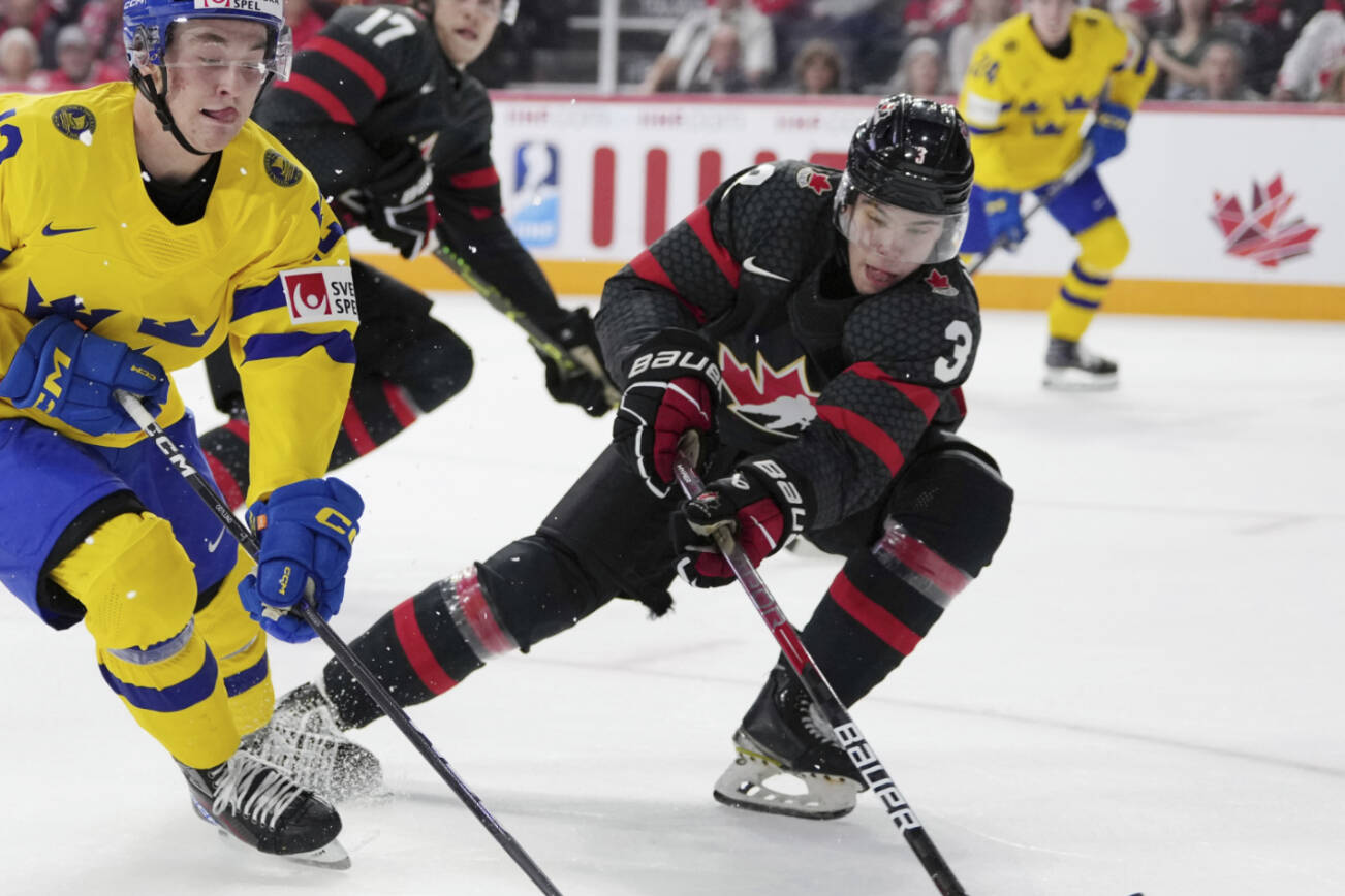 Sweden's Noah Ostlund, left, protects the puck from Canada's Olen Zellweger during an IIHF world junior hockey championships game Saturday, Dec. 31, 2022, in Halifax, Nova Scotia. (Darren Calabrese/The Canadian Press via AP)