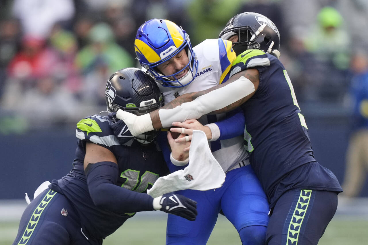 Los Angeles Rams quarterback Baker Mayfield, center, is tackled by Seattle Seahawks linebackers Bruce Irvin, right, and Uchenna Nwosu during the second half of a game Sunday, Jan. 8, 2023, in Seattle. (AP Photo/Stephen Brashear)