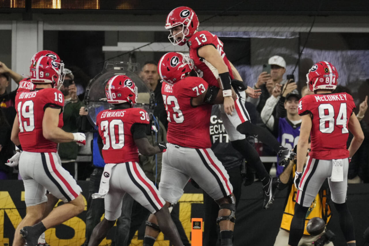 Georgia offensive lineman Xavier Truss (73) lifts Georgia quarterback Stetson Bennett (13) after Bennett scored a touchdown against TCU during the first half of the national championship game Monday in Inglewood, Calif. (AP Photo/Marcio Jose Sanchez)
