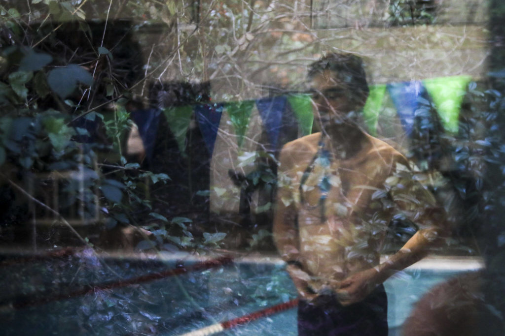 A reflection of a swimmer preparing to race during the Jackson vs. Kamiak boys swim and dive meet at West Coast Aquatics in Mill Creek, Washington on Tuesday Jan. 10, 2023. (Annie Barker / The Herald)
