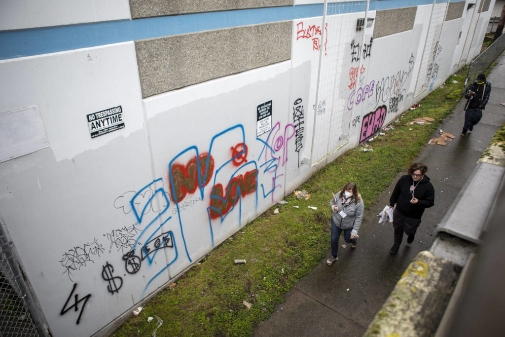 Point-in-time count volunteers walk under an overpass where several people live in cars and RVs during a point-in-time count of people facing homelessness on Tuesday in Everett. (Annie Barker / The Herald)
