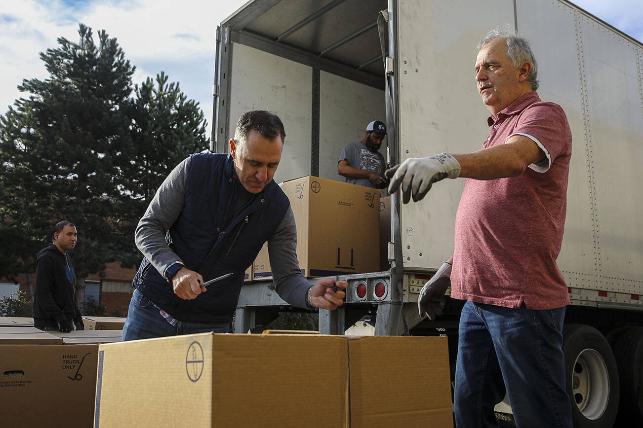 Store owner Jay Behar, 50, left, and store manager Dan Boston, 60, right, work to help unload a truck of recliners at Behar's Furniture on Monday, Jan. 16, 2023. Behar's Furniture on Broadway in Everett is closing up shop after 60 years in business. The family-owned furniture store opened in 1963, when mid-century model styles were all the rage. Second-generation owner, Jay Behar says it's time to move on. (Annie Barker / The Herald)