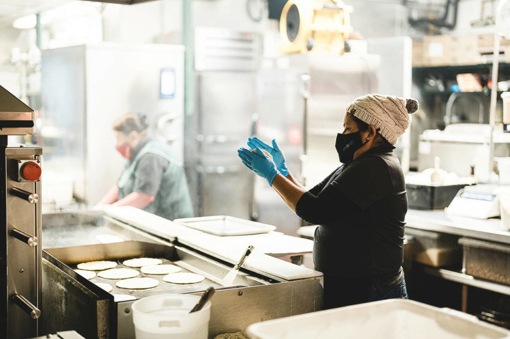 An employee makes tortillas by hand at La Palma Mexicatessen. (Mitch Dao / YES! Media)
