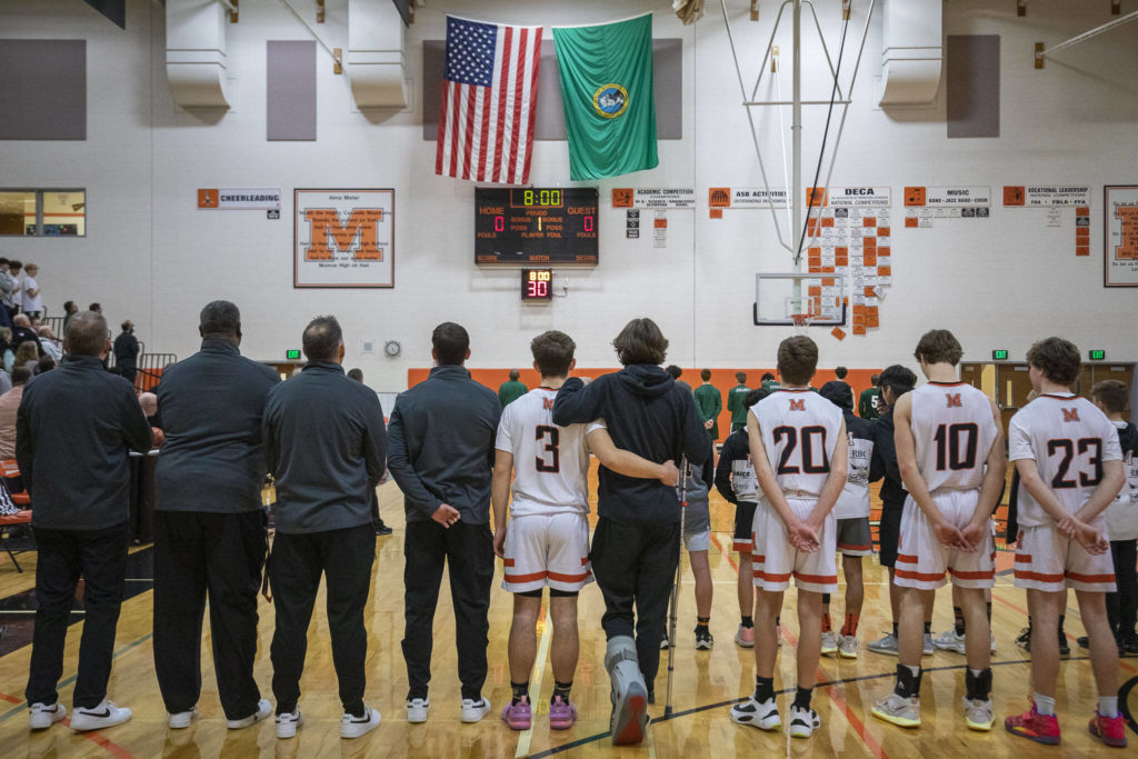 Monroe players and coaching staff stand for the national anthem during a game between the Monroe Bearcats and the Edmonds-Woodway Warriors at Monroe High School in Monroe, on Jan. 20. The Bearcats defeated the Warriors, 68-57. (Annie Barker / The Herald)
