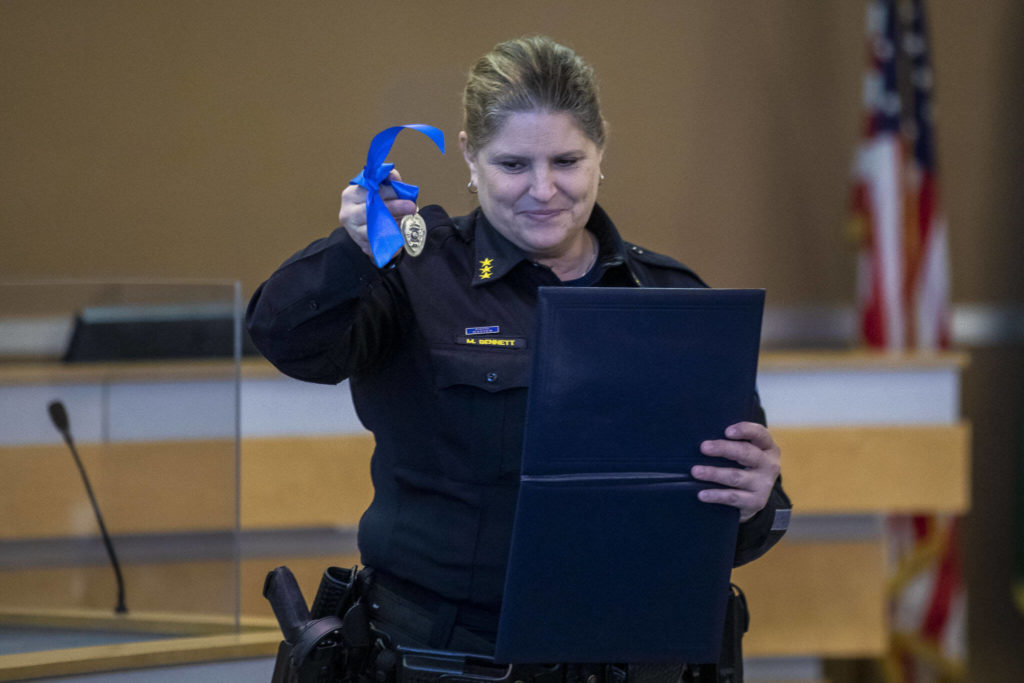 Edmonds Police Chief Michelle Bennett presents K-9 Hobbs and Sgt. Jason Robinson with a medal during Hobbs’ retirement ceremony at the Edmonds Police Department on Thursday, in Edmonds. (Annie Barker / The Herald)
