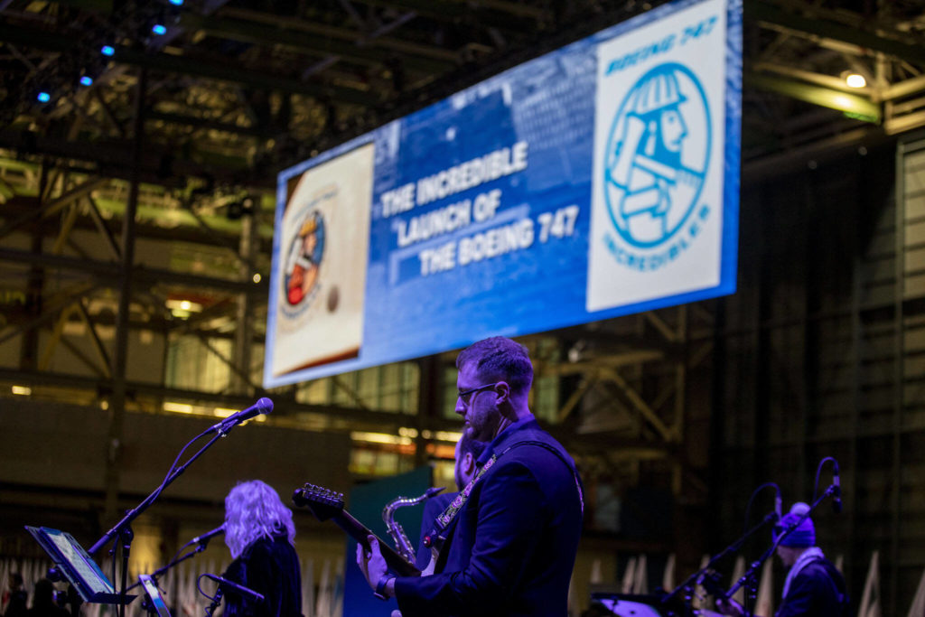 A band performs while videos play detailing the Boeing’s history on Tuesday during a celebration of the final 747 in Everett. (Annie Barker / The Herald)
