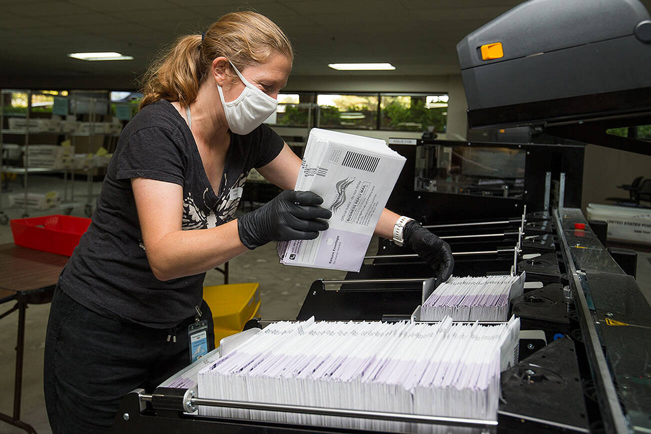 Catherine Berwicks loads ballots into a tray after scanning them at the Snohomish County Elections Ballot Processing Center on Tuesday, Aug. 4, 2020 in Everett, Wa.  (Andy Bronson / The Herald)