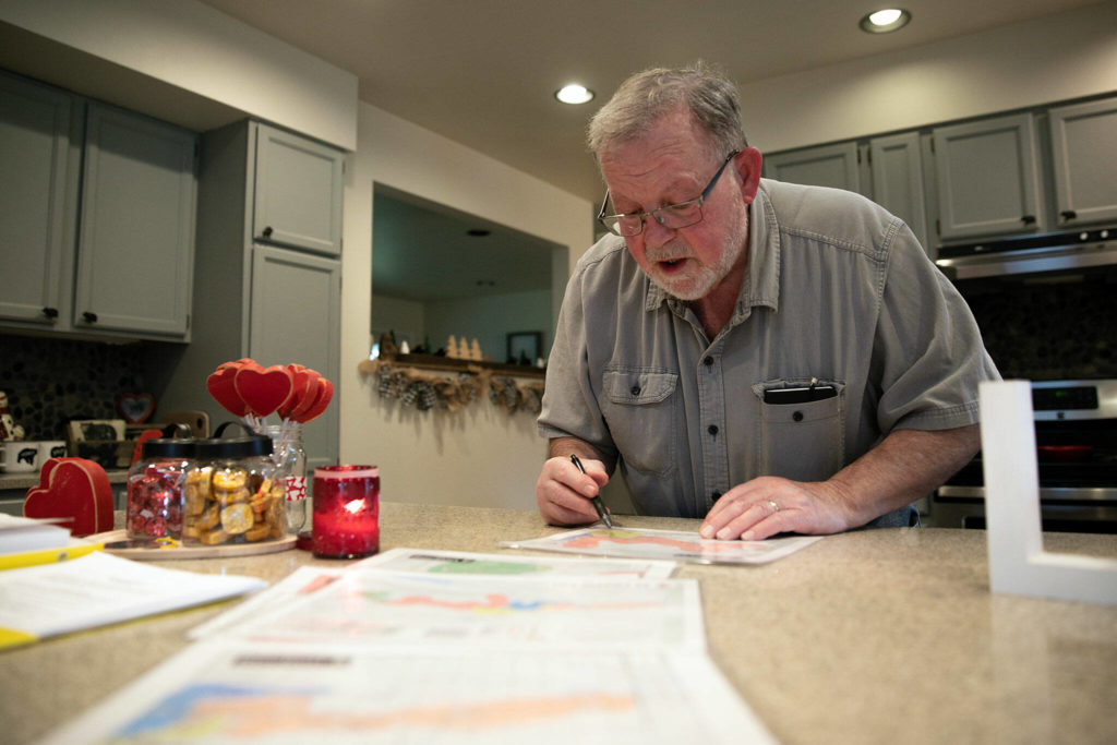 Ron Thompson looks over disaster planning maps of Oso at his home. (Ryan Berry / The Herald)
