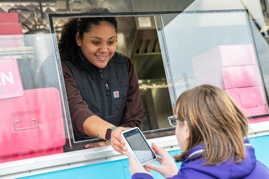 Kahlia Hamshaw takes orders at the food trailer, which was parked at the Beverly Food Truck Park at a busy south Everett intersection on opening day. (Ryan Berry / The Herald)
