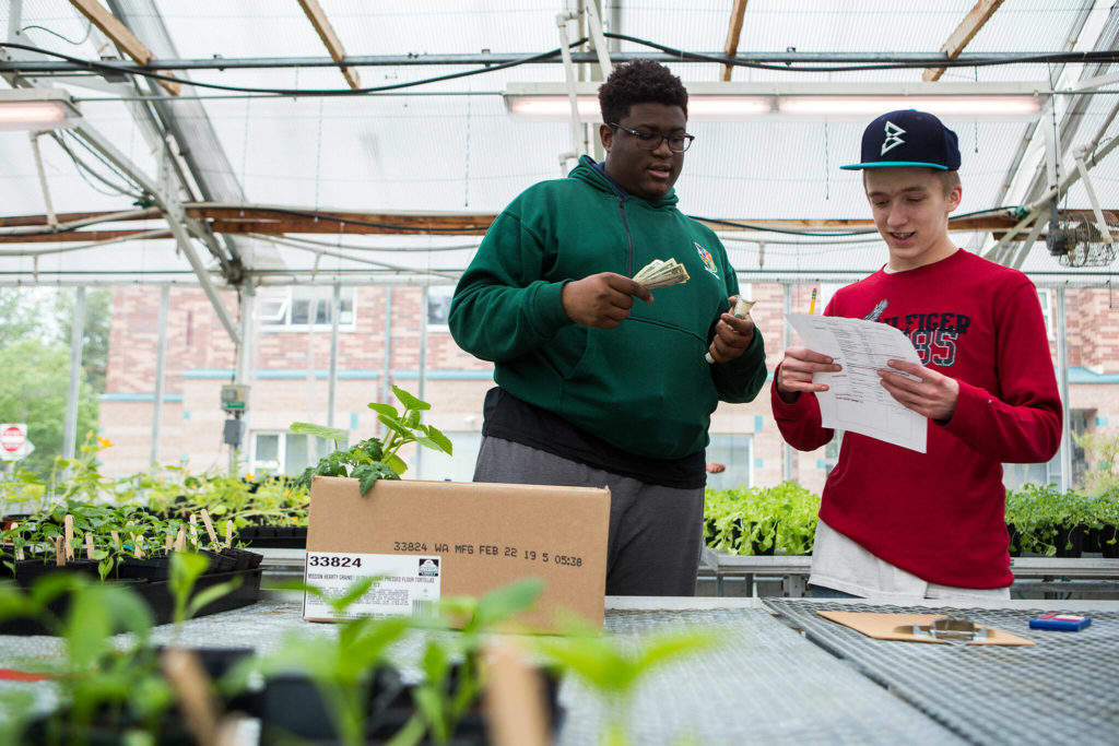 Alex Callaway, left, helps Isaac Henderson, right, double check his math for the final cost of his plant purchase during the Functional Life Academics plant sale at Kamiak High School on May 14, 2019 in Mukilteo. (Olivia Vanni / The Herald)
