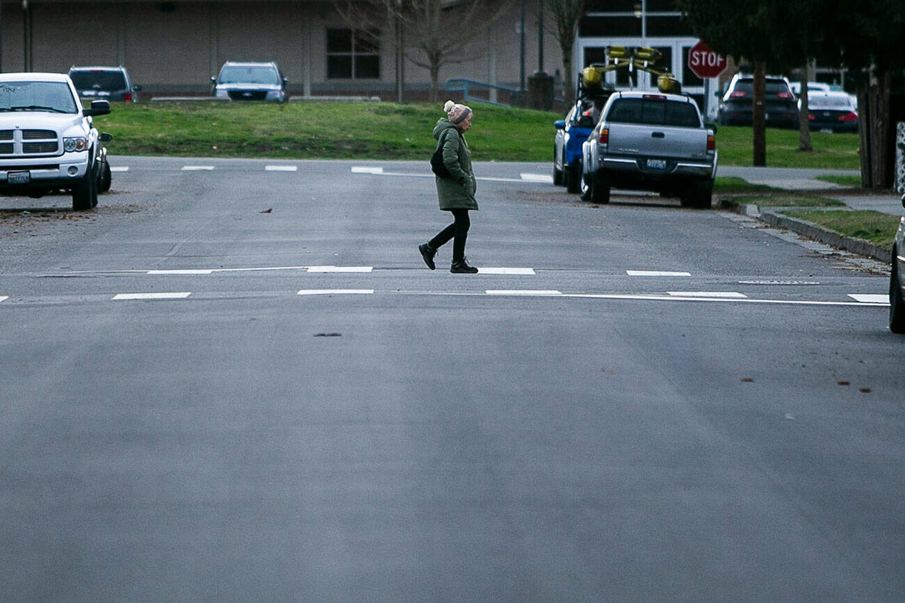 A pedestrian uses a cross walk to cross N Gifford Avenue on Thursday, Feb. 2, 2023 in Arlignton, Washington. (Olivia Vanni / The Herald)