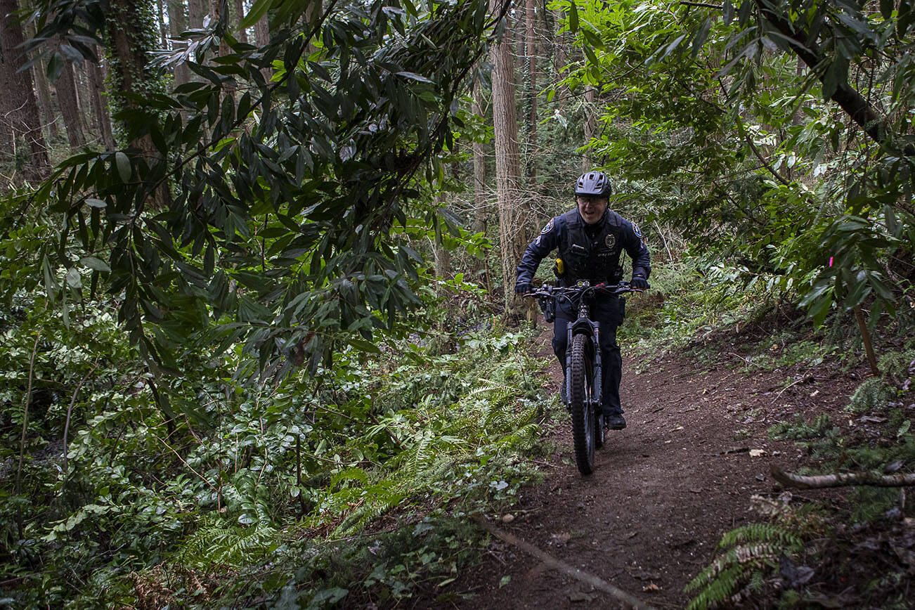 Police Officer Kyle O’Hagan demonstrates riding techniques with a new electric-assisted mountain bike near the Mountlake Terrace Police Department in Mountlake Terrace, Washington, on Sunday, Feb. 5, 2023. (Annie Barker / The Herald)