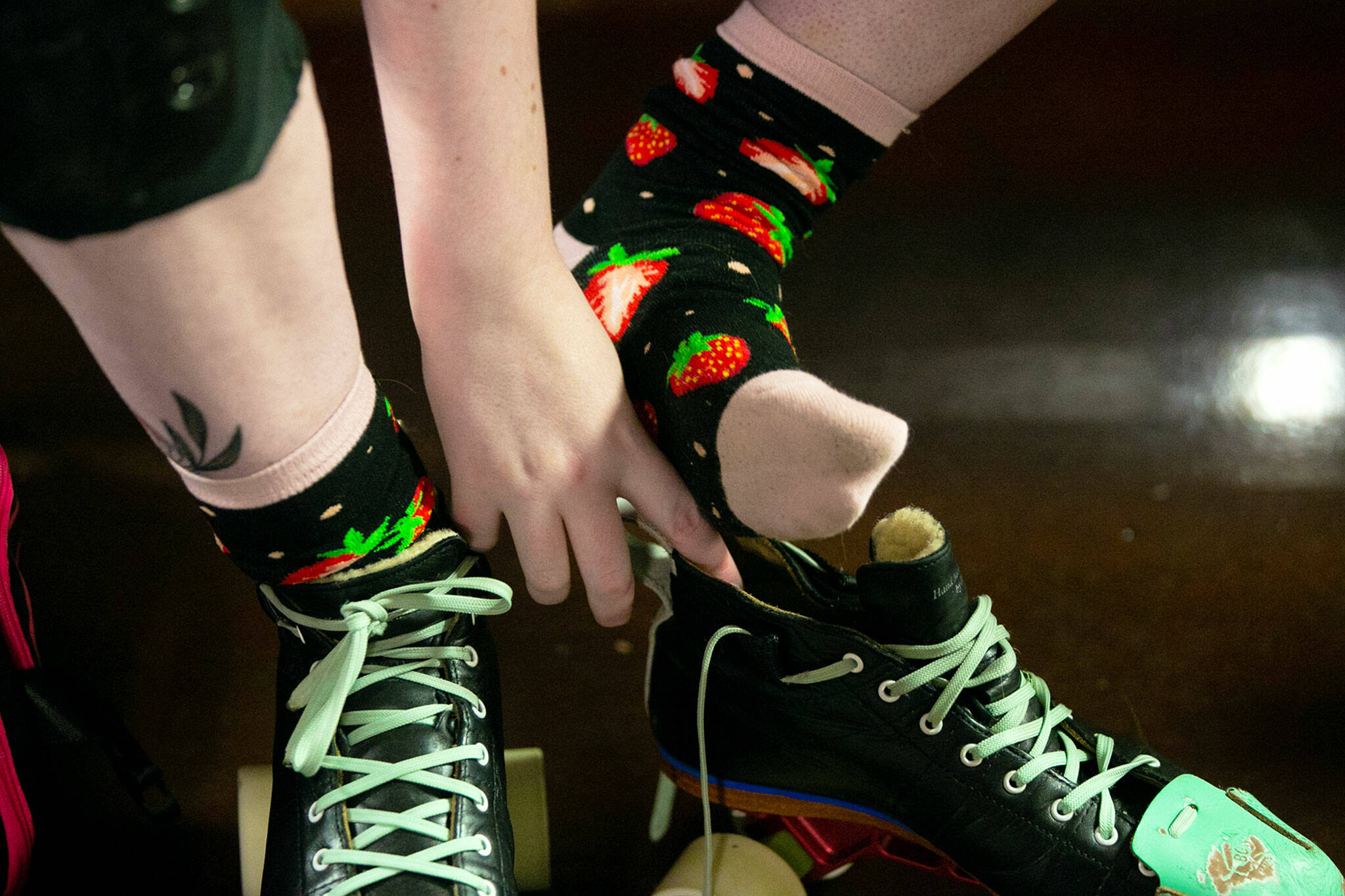 “Rina Rock You” Marina Kolbeck dons strawberry socks while putting on gear during a Strawberry City Roller Derby practice at Marysville Skate Center on Monday, Feb. 6, in Marysville. (Ryan Berry / The Herald)