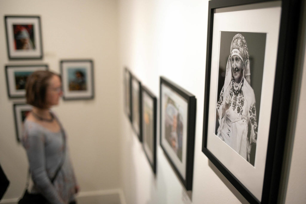 A woman peruses a corner of photographic prints by multiple Ukrainian artists during a public event highlighting the For Ukraine: Art of Freedom exhibit at the Schack Art Center on Saturday, in downtown Everett. (Ryan Berry / The Herald)
