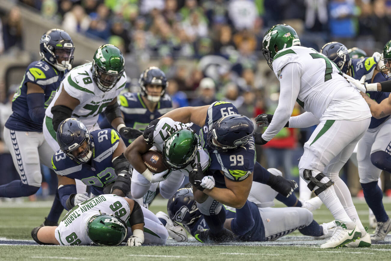 Seattle Seahawks defensive tackle Al Woods (99) tackles New York Jets running back Zonovan Knight (27) in an NFL football game, Sunday, Jan. 1, 2023, in Seattle, Wash. Seahawks won 23-6. (AP Photo/Jeff Lewis)