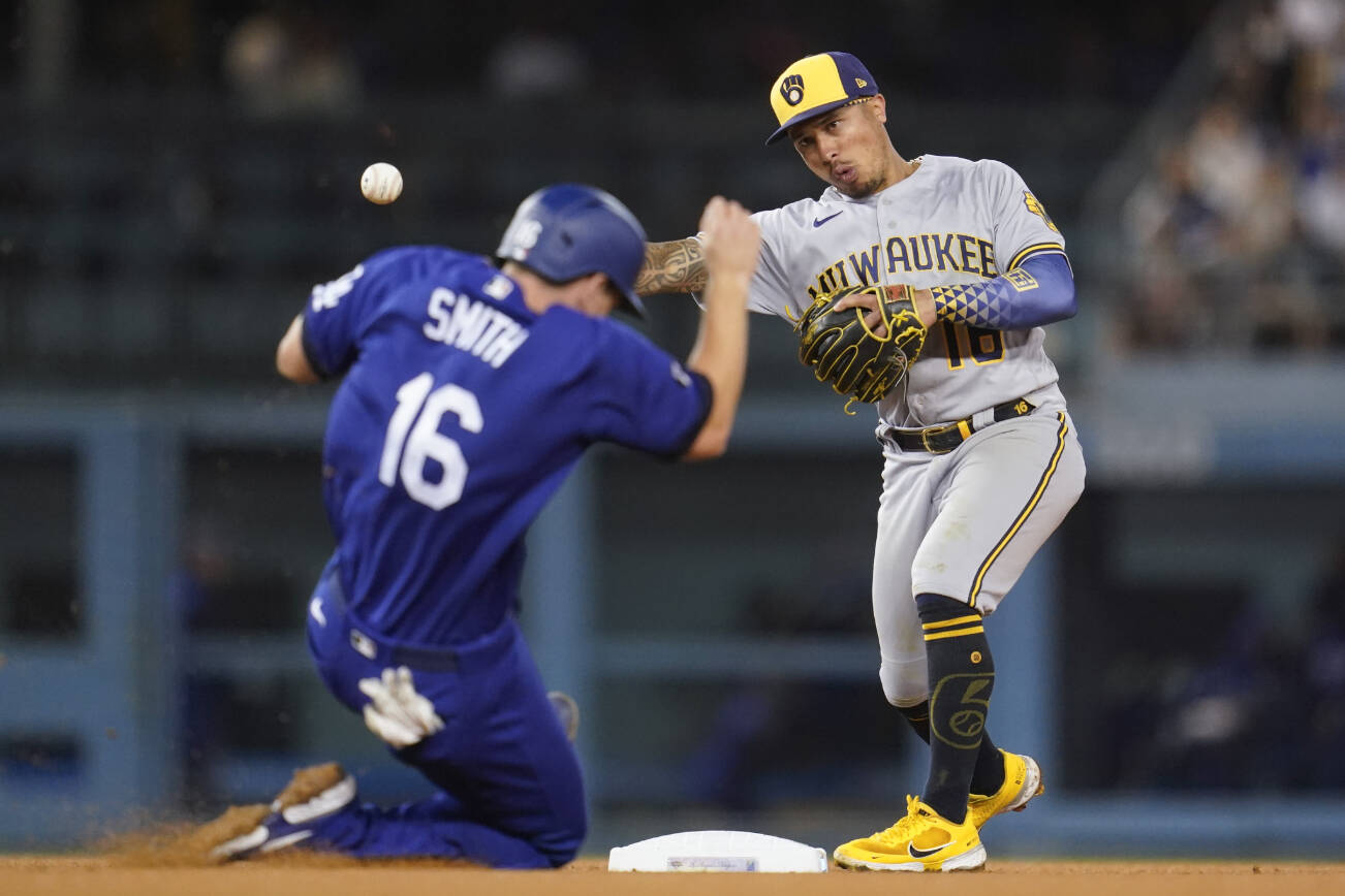 Milwaukee Brewers second baseman Kolten Wong (16) throws to first for double play during the eighth inning of a baseball game Los Angeles Dodgers in Los Angeles, Monday, Aug. 22, 2022. Los Angeles Dodgers designated hitter Justin Turner grounded in to a double play. Will Smith (16) was out at second and Turner was out at first. (AP Photo/Ashley Landis)