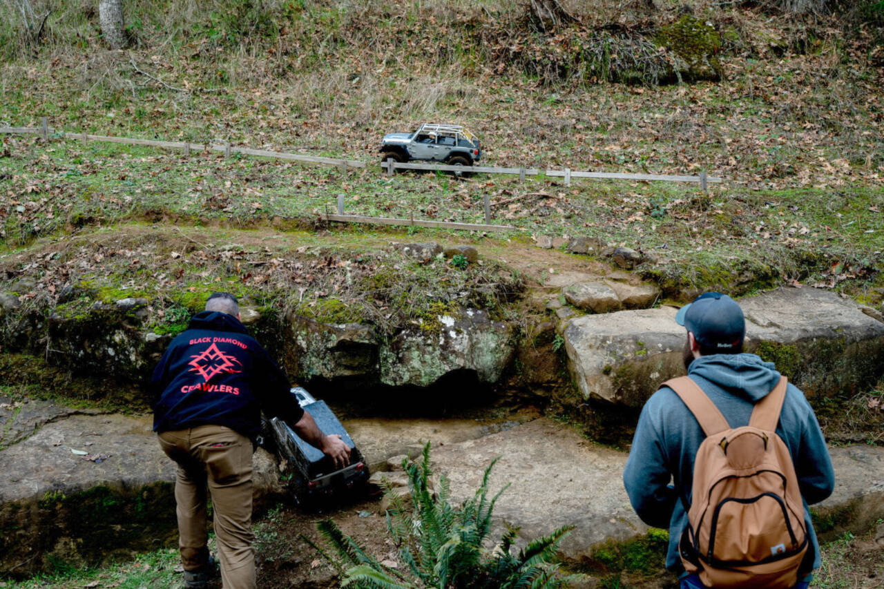 Jared Valencourt (right) drives his RC car along a hill as Scott Haury picks up his car after it plunged down an embankment. (Roseburg News-Review)