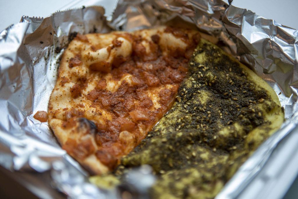 Half of a muhammara manakish and a za’atar manakish from Alidas Bakery in Everett. All manakish profits from Feb. 9 to Feb. 16 will be donated to help earthquake victims in Syria and Turkey. (Annie Barker / The Herald)

