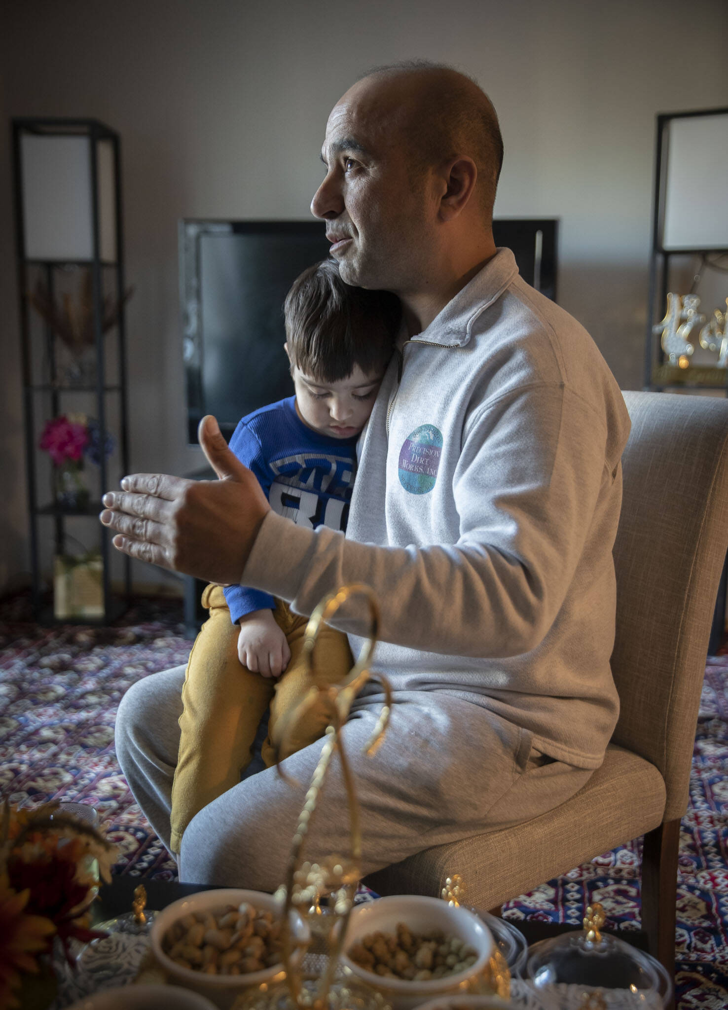 Mohammad Zamir Omar speaks about his family’s journey from Afghanistan while his 3-year-old son sleeps on his lap at their home on Tuesday, in Lynnwood. (Olivia Vanni / The Herald)