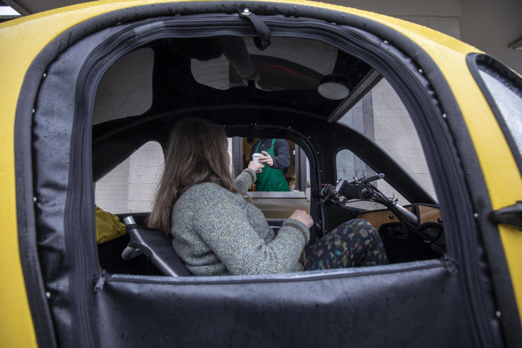 Paula Townsell pedals her PEBL in a Starbucks drive-thru in Everett. (Annie Barker / The Herald)
