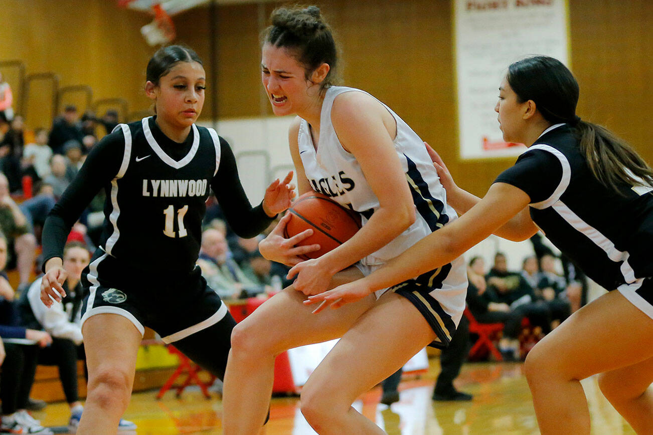 Arlington’s Jenna Villa muscles the ball away from the offense for a rebound against Lynnwood on Tuesday, Feb. 14, 2023, at Marysville Pilchuck High School in Marysville, Washington. (Ryan Berry / The Herald)