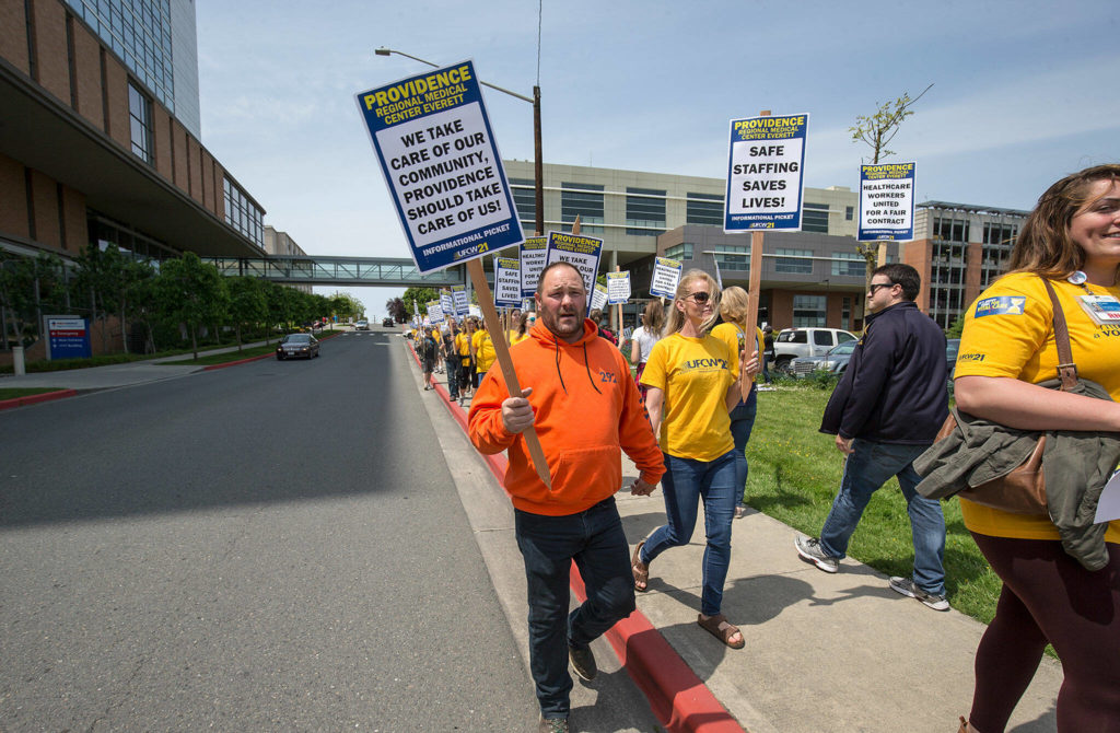 Katy Roth, a nurse, and her husband Rod, a union member with Labor Local 292, walk hand in hand on June 6, 2018, during a picket at Providence Regional Medical Center Everett in Everett. (Andy Bronson / Herald file)
