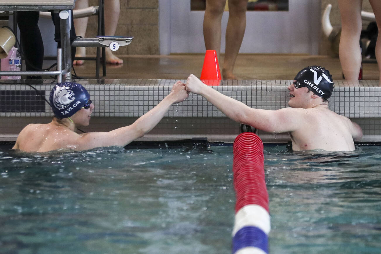 Lake Stevens’ Garrett Chesley, right, and Glacier Peak’s Kaiu Taylor, left, fist-bump after a race during the 4A District 1 swim and dive championships at Snohomish Aquatic Center, in Snohomish, Washington on Saturday, Feb. 11, 2023.  (Annie Barker / The Herald)