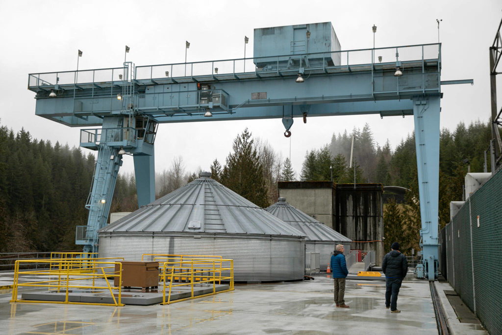 Snohomish County PUD generation engineering manager Scott Spahr and media liaison Aaron Swaney walk along the top deck of the Henry M. Jackson Powerhouse on Friday near Sultan. The plant’s two most powerful generators are covered by the “grain silos” at left. (Ryan Berry / The Herald)
