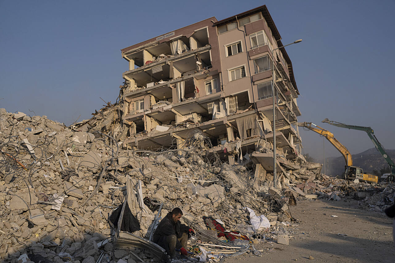 A man sits in the rubble of collapsed collapsed building in Antakya, Turkey, Feb. 12. Days after two powerful earthquakes hours apart caused scores of buildings to collapse, killing thousands of people and leaving millions homeless, rescuers were still pulling unlikely survivors from the ruins. (Petros Giannakouris / Associated Press)