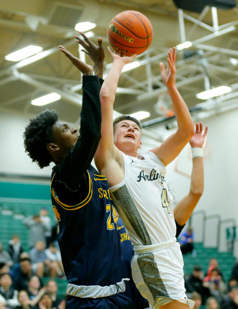 Arlington’s Ty Rusko tries to get an acrobatic shot to fall against Shorecrest on Wednesday, Feb. 15, 2023, at Jackson High School in Mill Creek, Washington. (Ryan Berry / The Herald)
