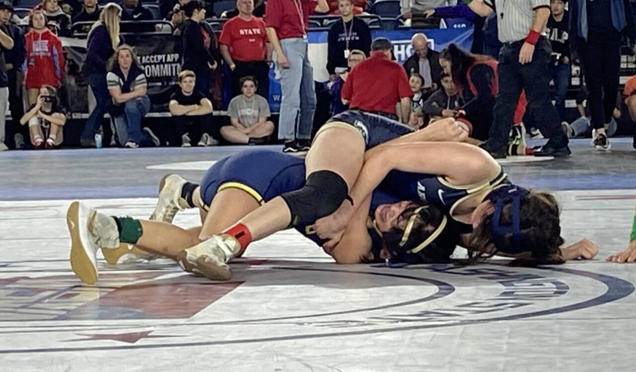 Arlington’s Danielle Crew (top) wrestles Kelso’s Bella Victoriano in the quarterfinals of the 4A/3A girls 115-pound weight class during the first day of Mat Classic XXXIV on Feb. 17, 2023, at the Tacoma Dome. Crew won by pinfall to reach the state semifinals. (Zac Hereth / The Herald)