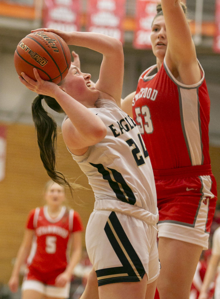 Arlington’s Katie Snow attempts a layup while guarded during the game against Stanwood on Saturday, Feb. 18, 2023 in Everett, Washington. (Olivia Vanni / The Herald)
