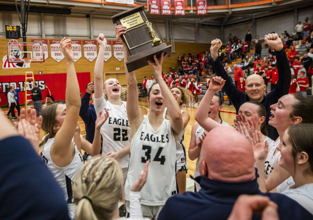 Arlington’s Jenna Villa lifts the 3A District 1 championship trophy in the air on Saturday, Feb. 18, 2023 in Everett, Washington. (Olivia Vanni / The Herald)
