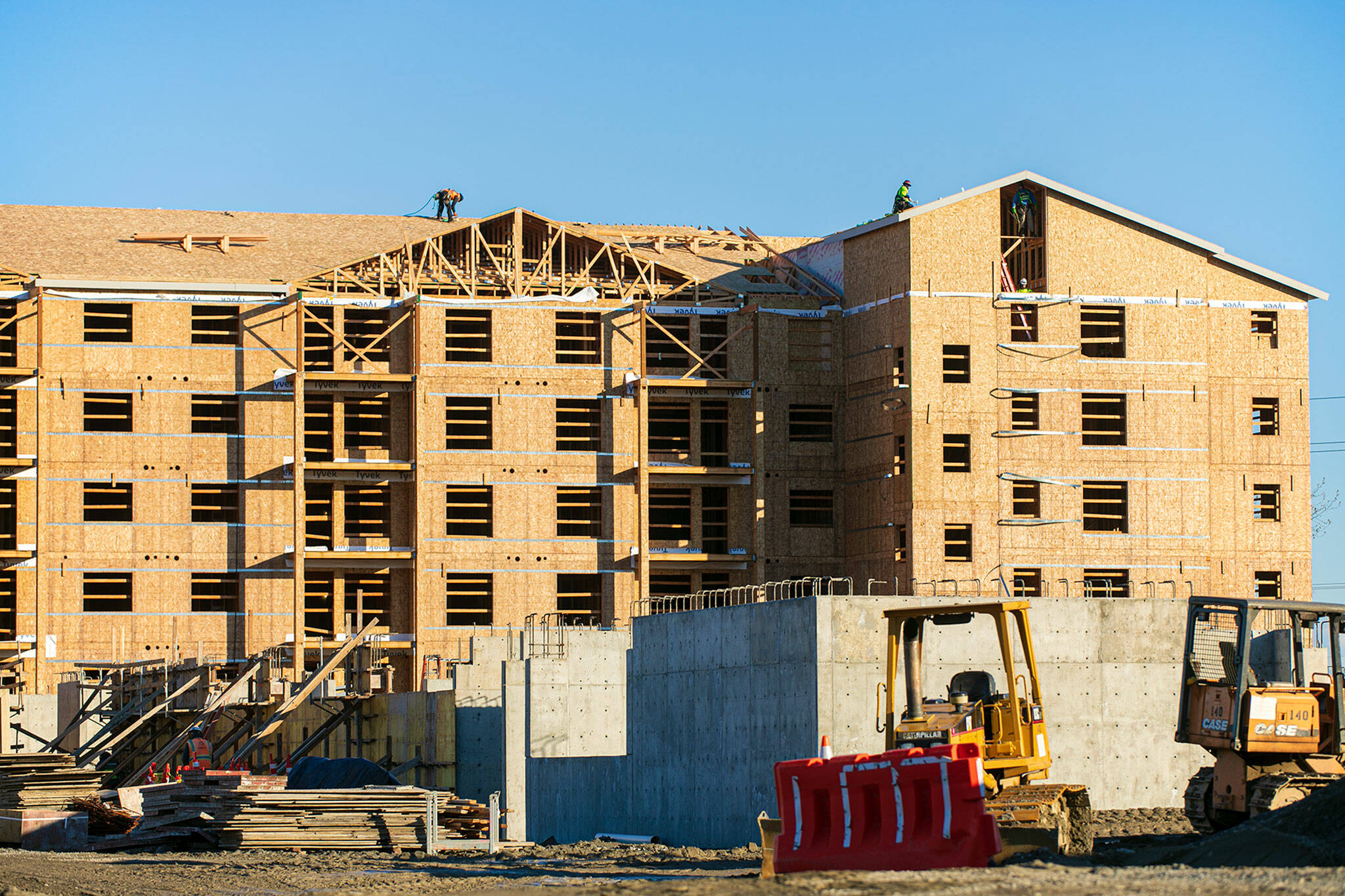 Builders work on the roof of one of the buildings at the Four Corners Apartments on Beverly Lane near Evergreen and 79th Place SE, in November, in Everett. (Ryan Berry / The Herald file photo)