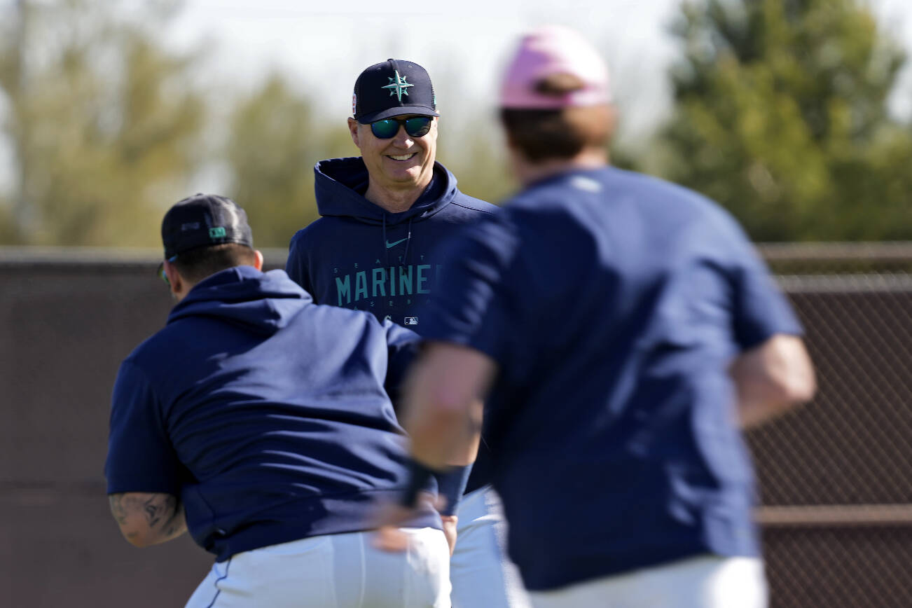 Seattle Mariners manager Scott Servais watches players warmup during spring training baseball practice Saturday, Feb. 18, 2023, in Peoria, Ariz. (AP Photo/Charlie Riedel)