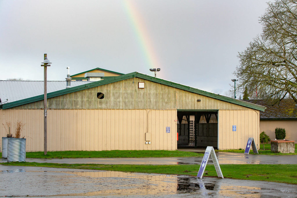A rainbow forms above Commercial Building No. 400 following an event celebrating the impending demolition of the outdated building on Tuesday, at the Evergreen State Fairgrounds in Monroe. (Ryan Berry / The Herald)
